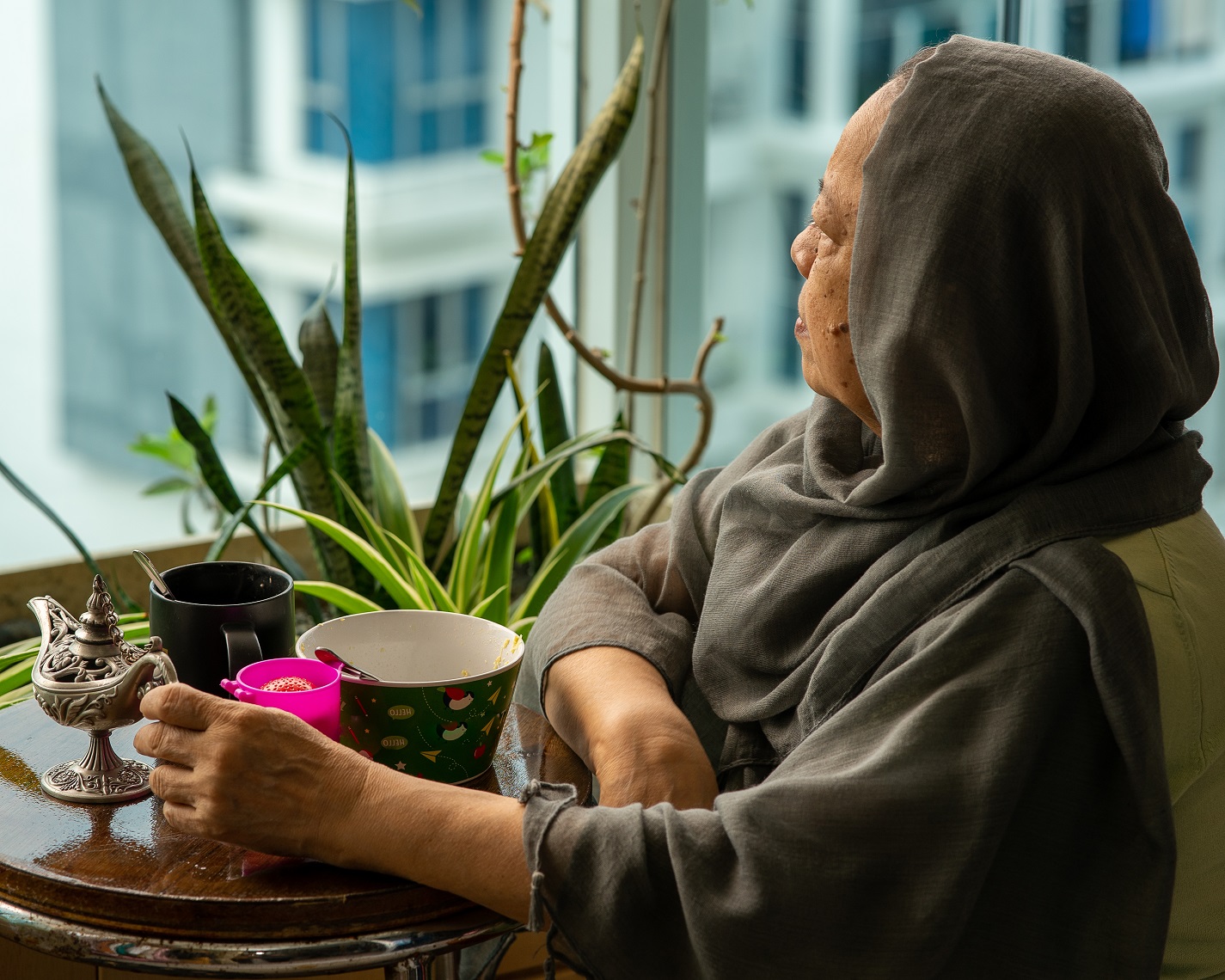 Senior Malaysian Muslim woman stay at home. Looking out from the